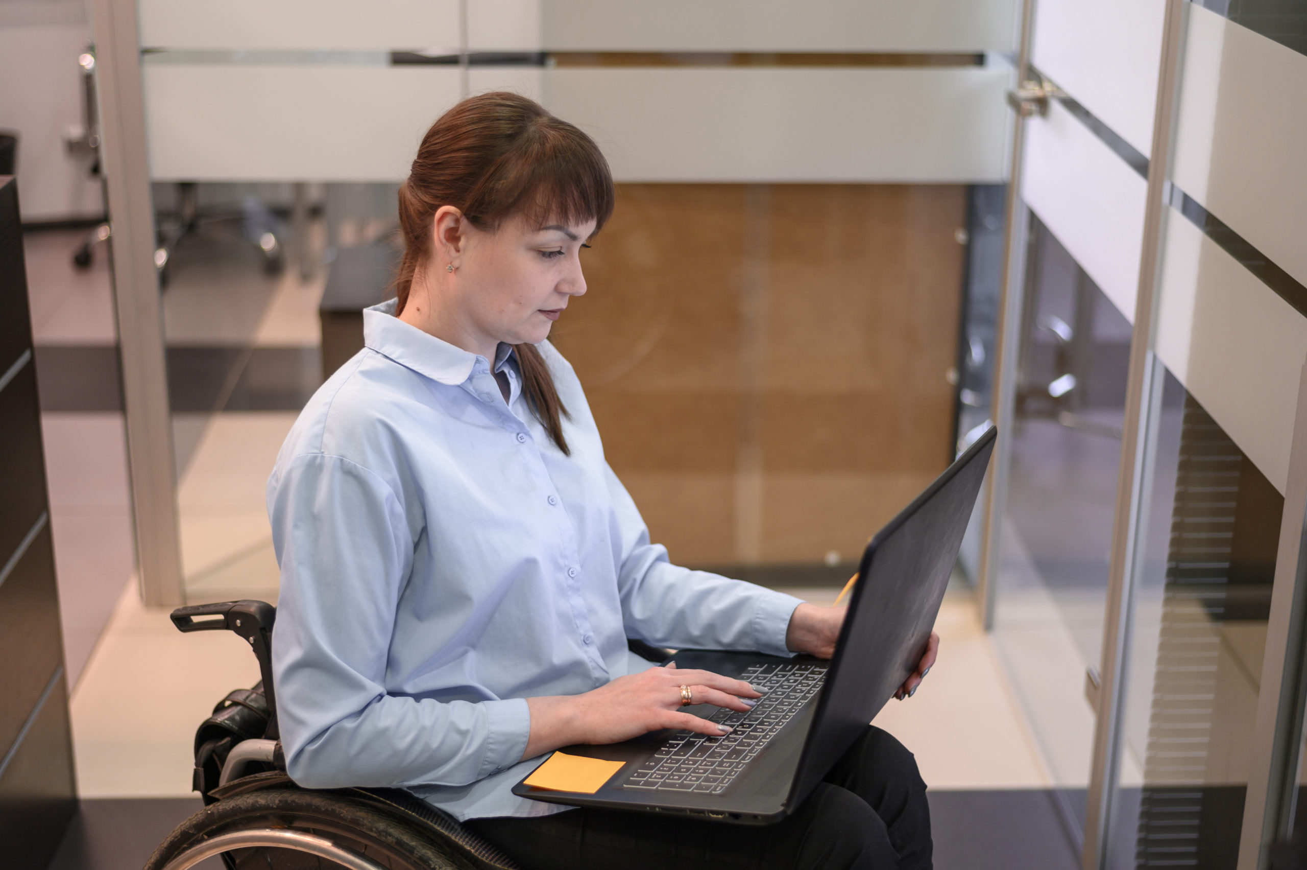 handicapped-young-woman-in-office-working-on-laptop